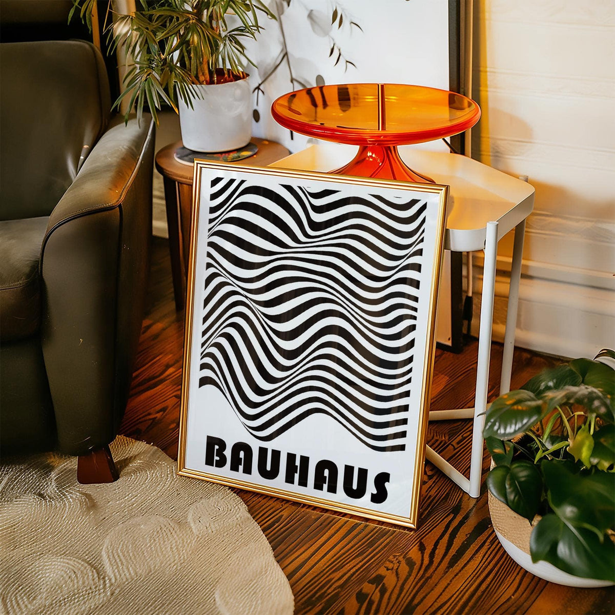 Print leaning on the floor with wavy black and white stripes near a green armchair and houseplants