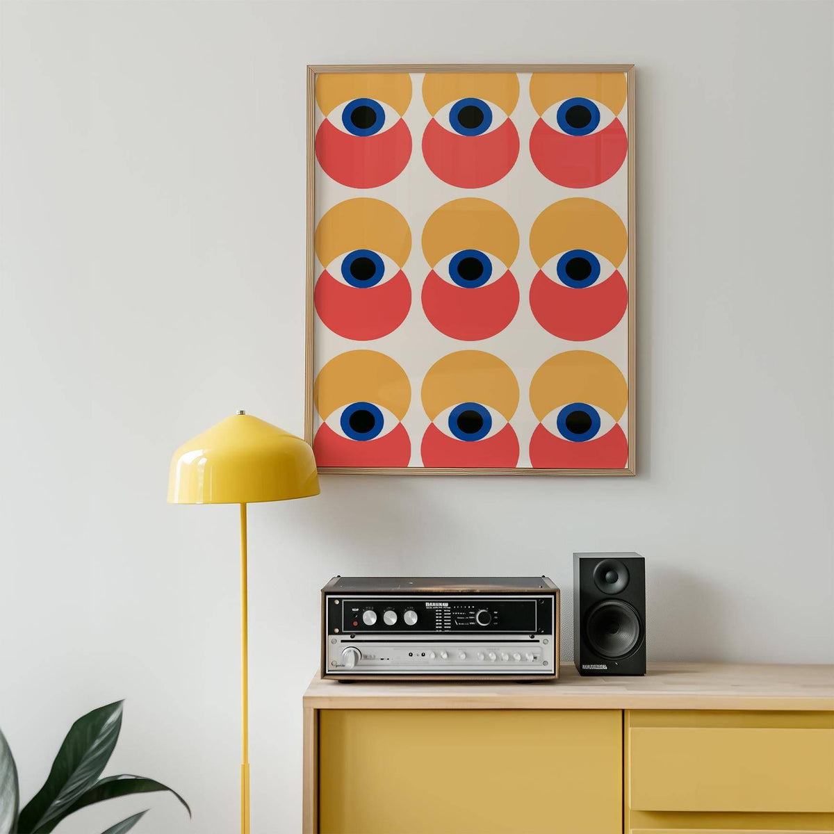 Wall Art Eye framed print of abstract eyes in yellow and red above a stereo on a yellow cabinet