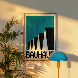 Framed Bauhaus Poster Blue with abstract stepped rooftops and bold typography beside a blue lamp and green plant
