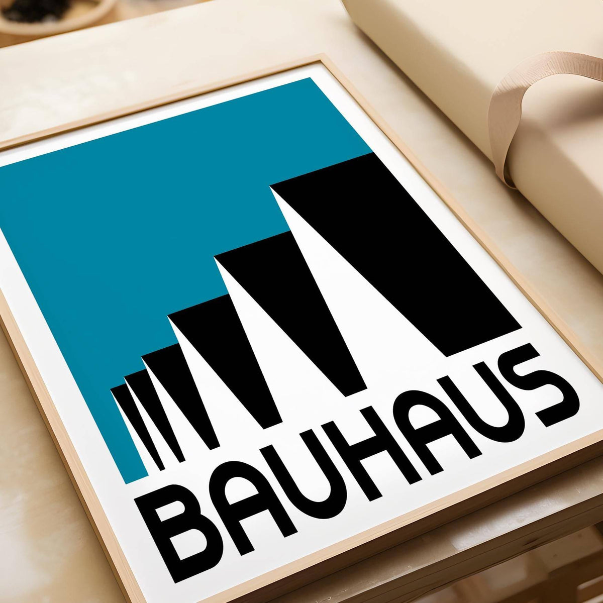 Framed close-up of Bauhaus Poster Blue with abstract stepped rooftops in black and blue on a flat surface