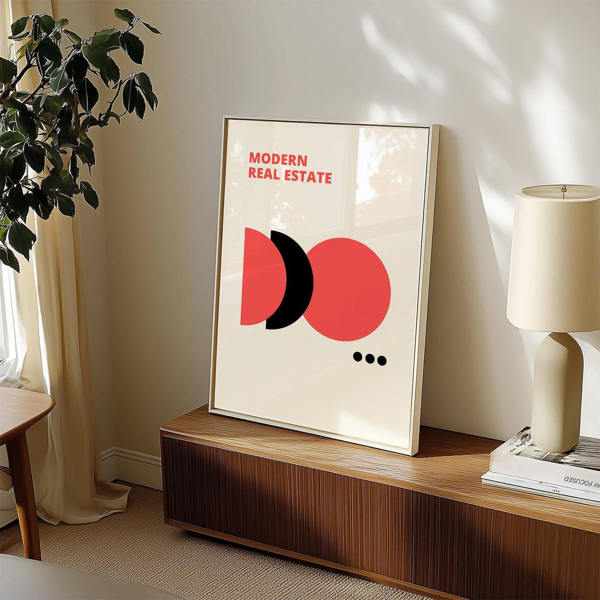 Red Black and White wall art with modern real estate text in a frame on a wooden sideboard with a lamp and plant nearby