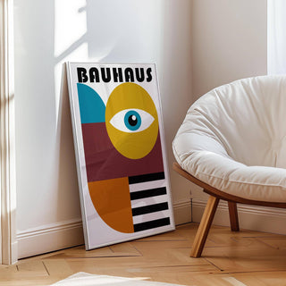 Print leaning on floor of retro wall art with blue, mustard and rust shapes beside white cushioned chair