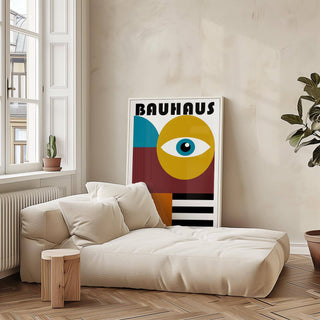 Retro wall art with stylized eye graphic in blue and ochre leaning against a neutral wall beside a leafy plant