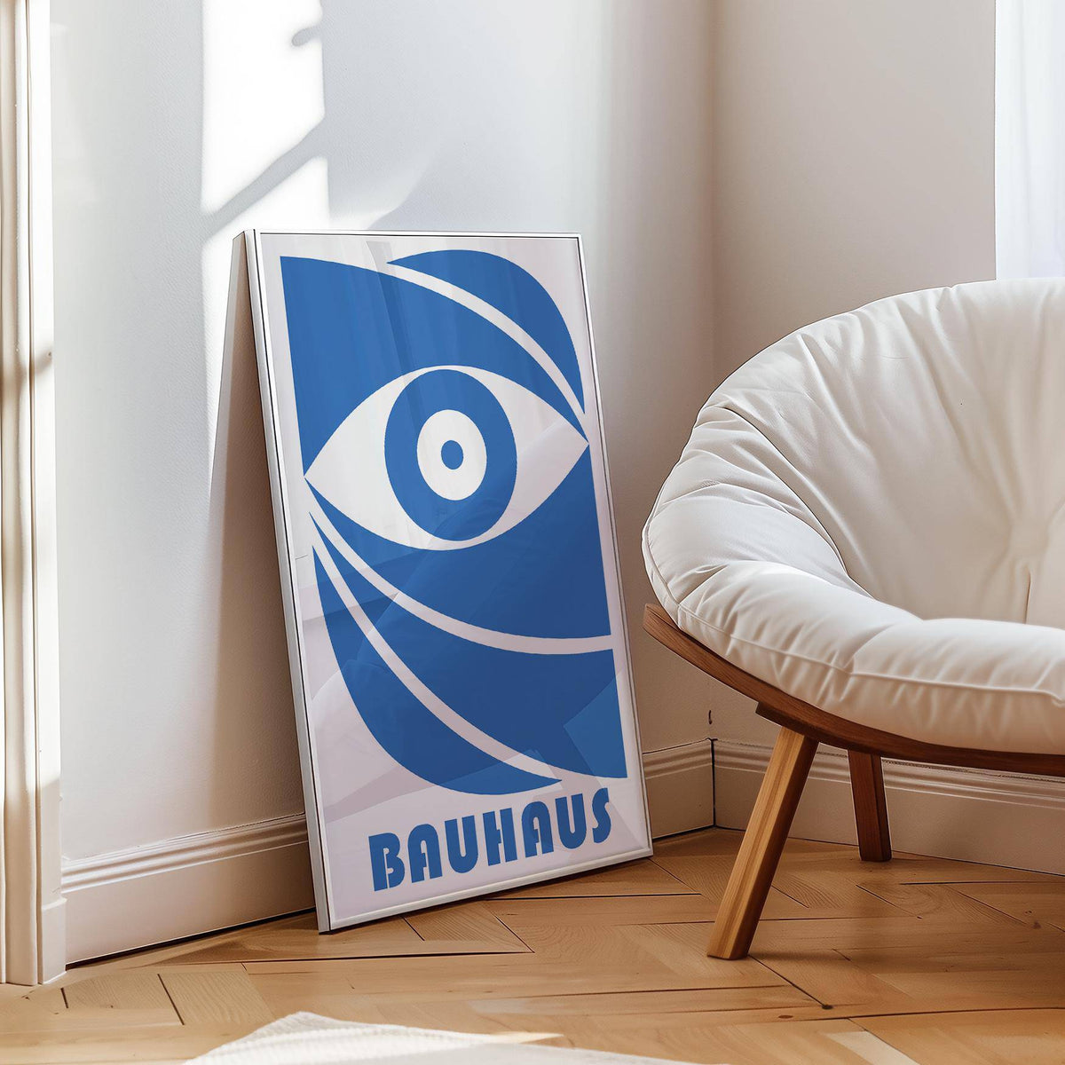 Print leaning on floor with blue stylised eye and typographic elements near a white cushioned chair