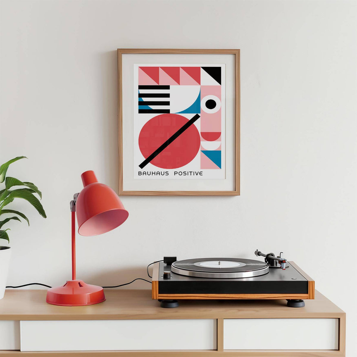 Colorful Geometric Art print with red blue and black shapes above a record player and red lamp