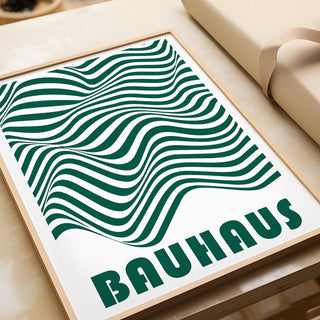 Close-up of green and white wall art with wavy stripes and Bauhaus lettering on a table
