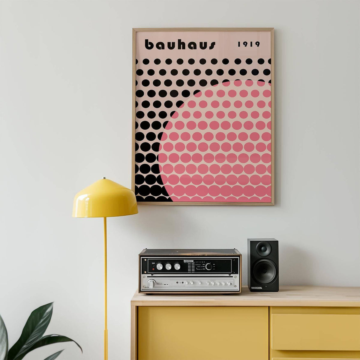 Bauhaus print poster with pink circle and black dots above a mustard sideboard with vintage stereo and yellow lamp
