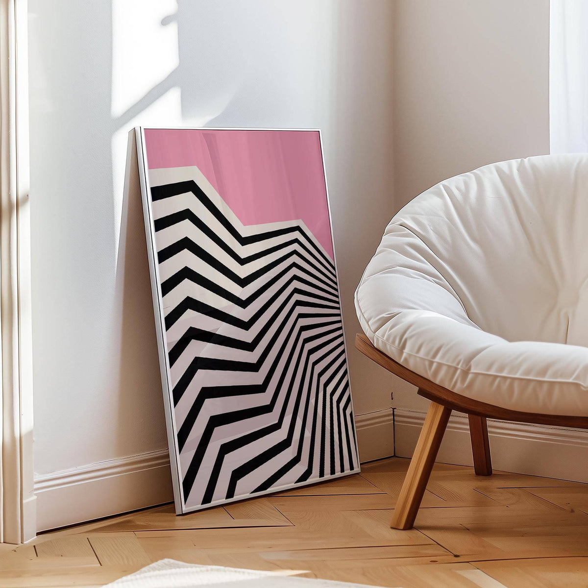 Print leaning on floor with black and white zigzag and pink background next to white chair