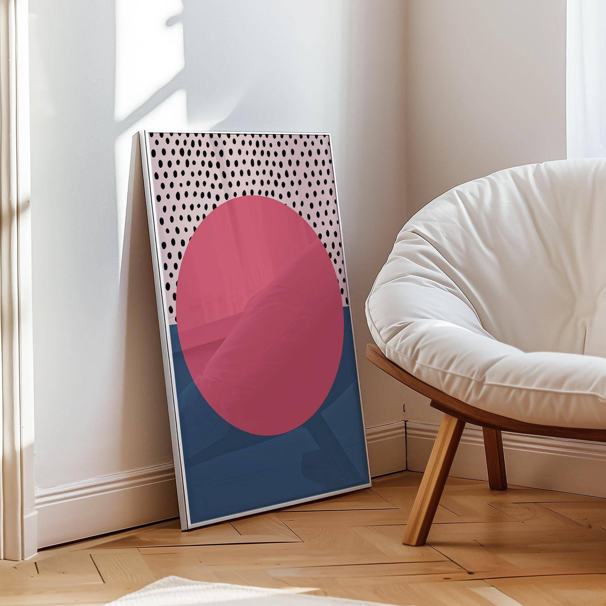 Print leaning on the floor of modern abstract art geometric with a pink circle and black dots near a white chair