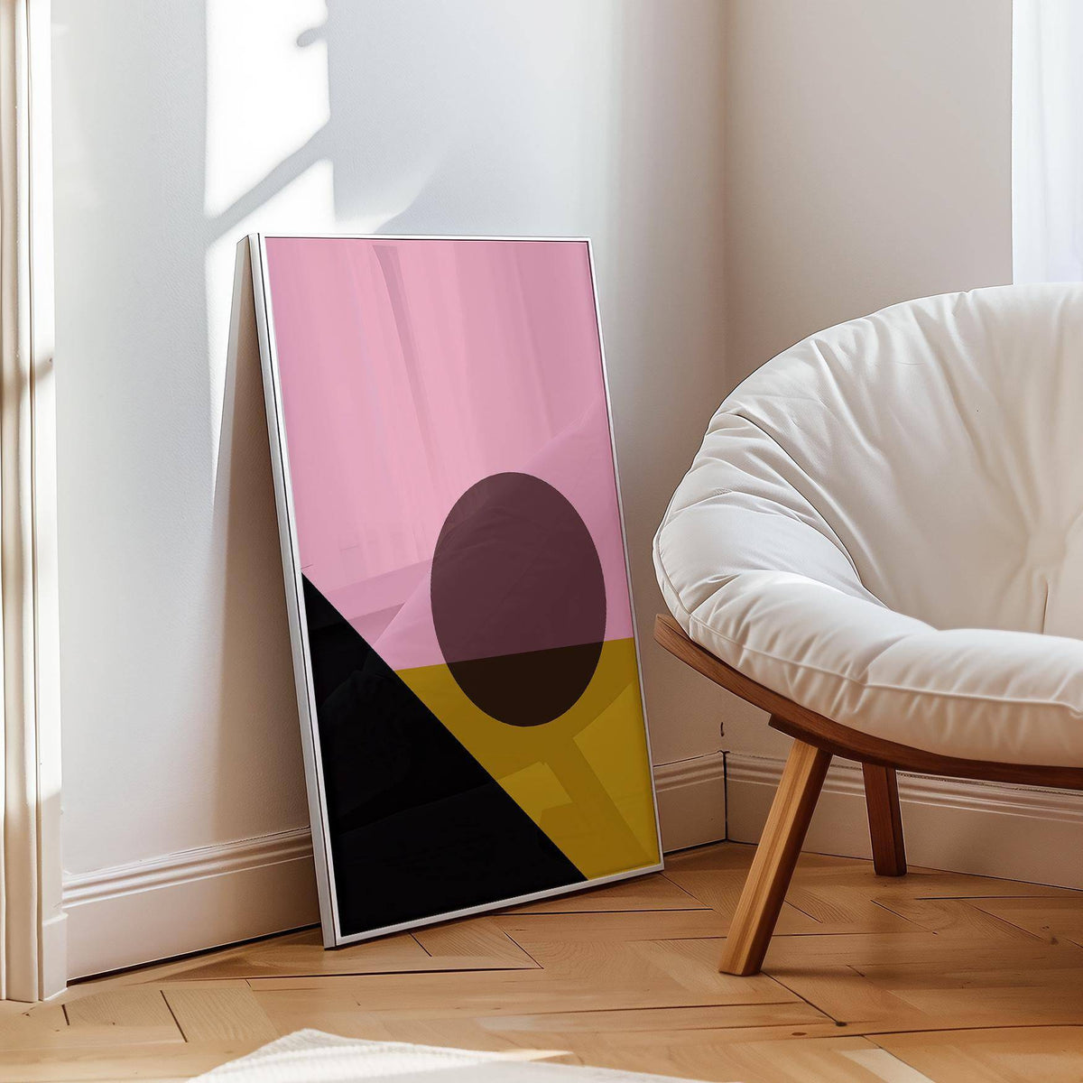 Bright Colored Artwork leaning on a wooden floor with soft chair nearby showing abstract mountain and sun in pink and yellow