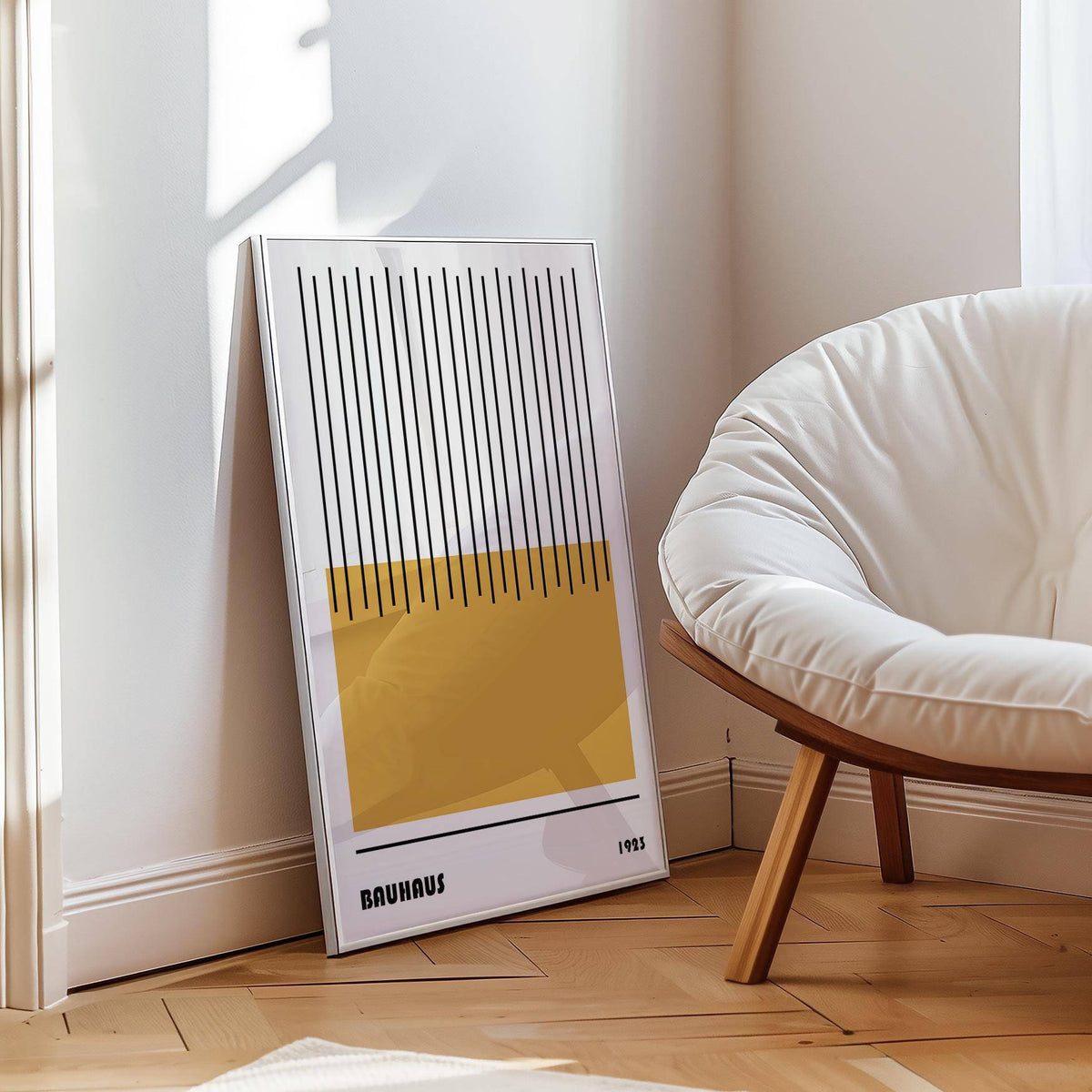 Print leaning on floor featuring modern geometric art with yellow rectangle and black lines near a white cushioned chair