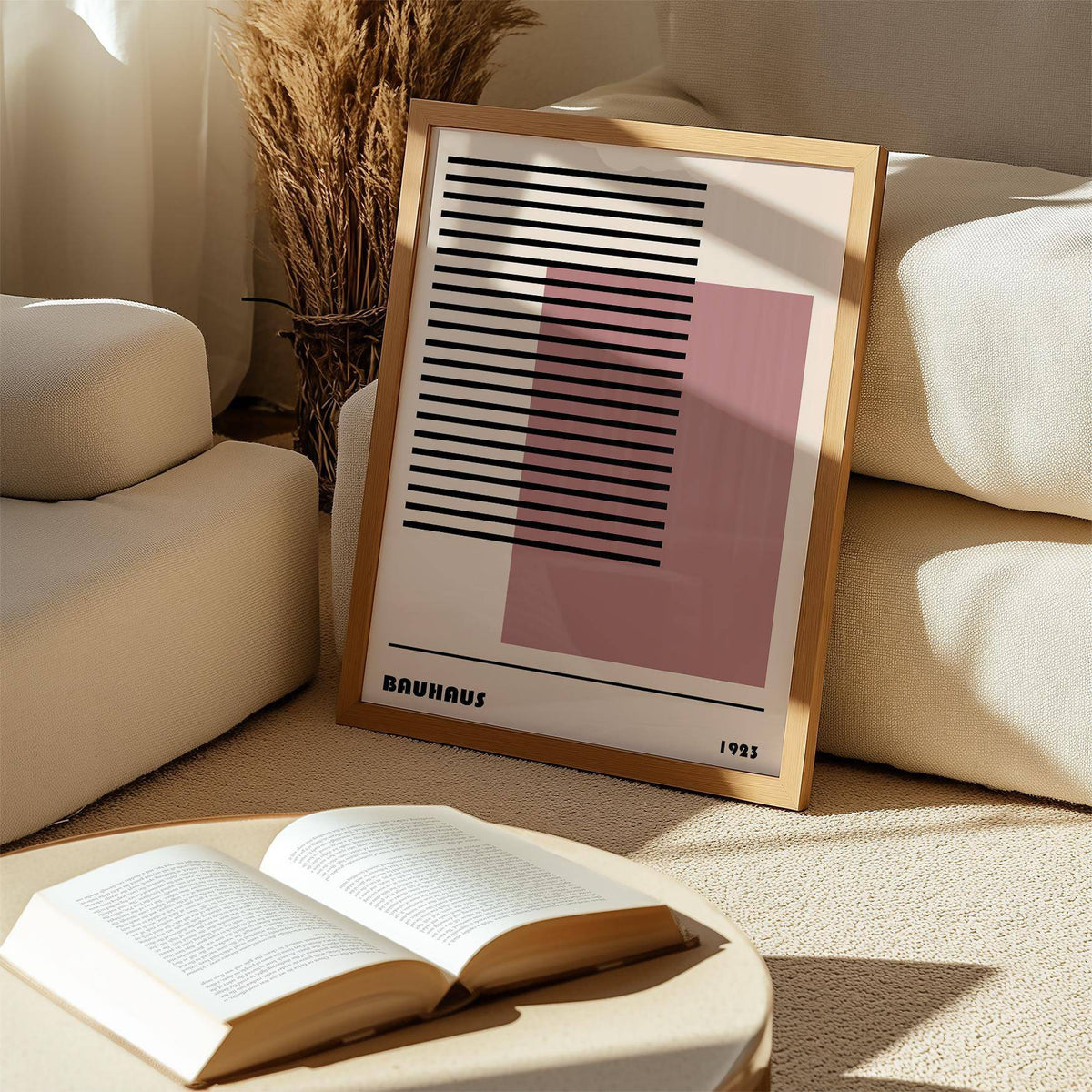 Print leaning on the floor of Bauhaus 1923 Art with black lines and a pink square near a beige sofa