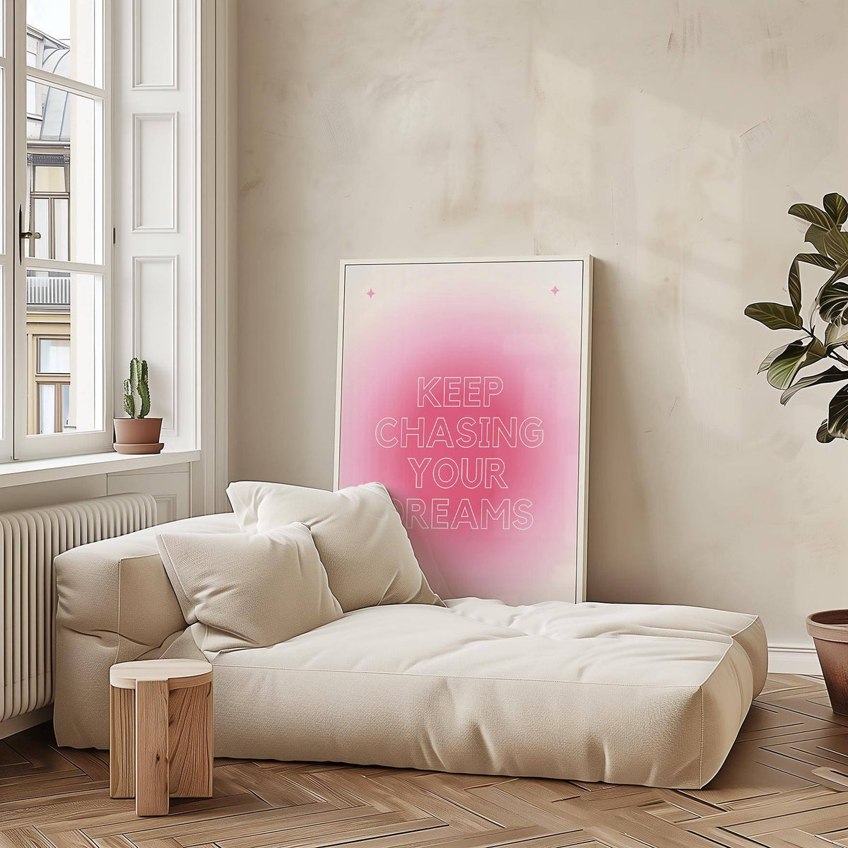 Print leaning on a beige sofa with soft cushions and wooden floor framing a motivational pink and white typographic design