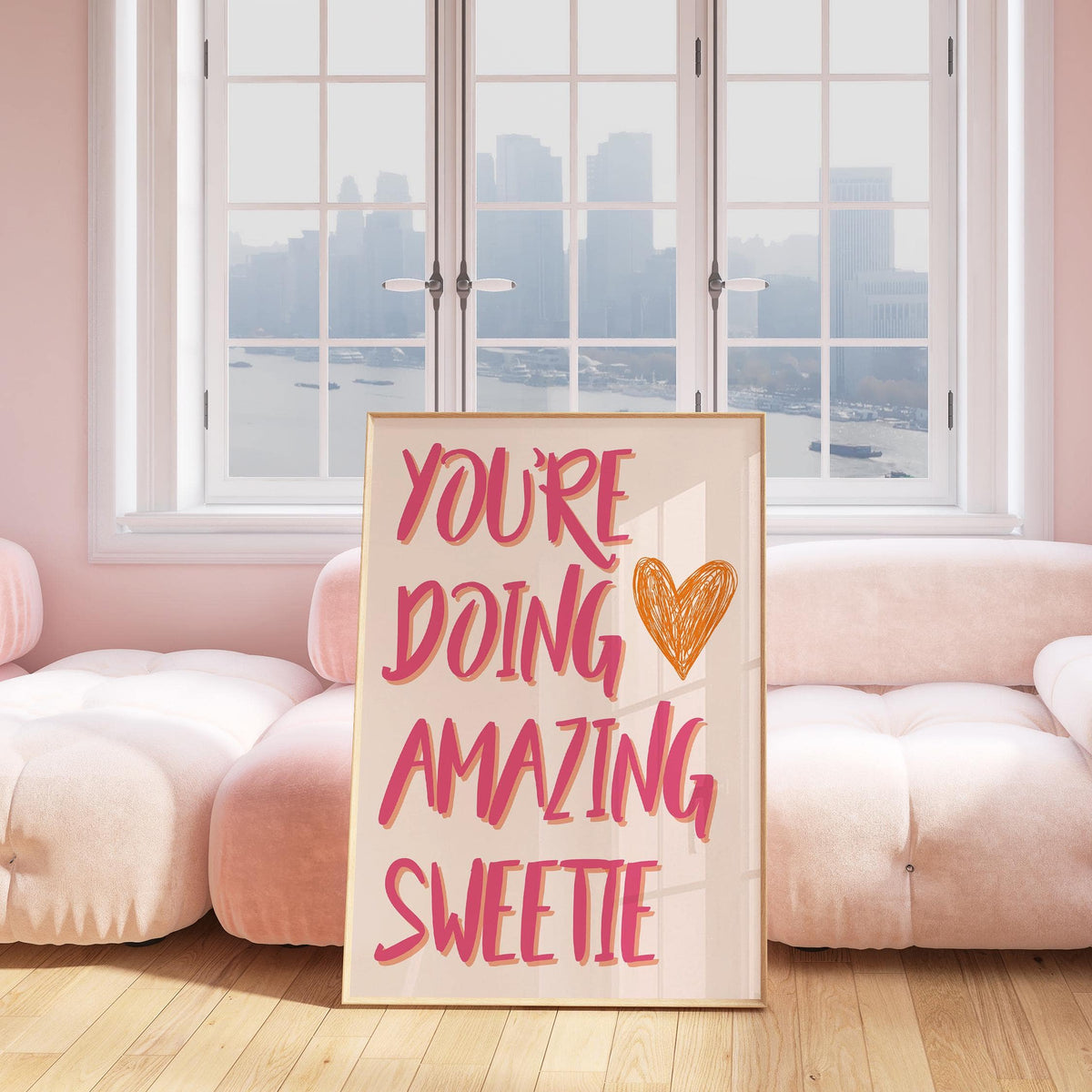 Good Motivational Posters with pink and orange handwritten text leaning on a pink sofa