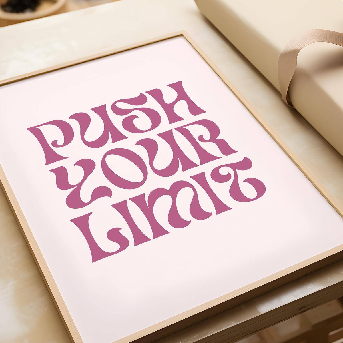 Framed Push Your Limit quote motivational poster with bold pink typography on pale background on a table