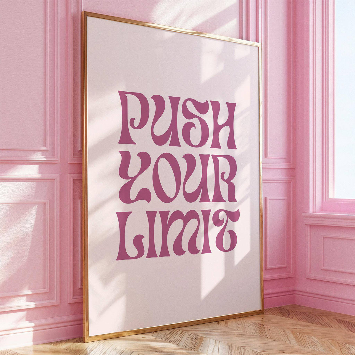 Framed print of a motivational quote in pink against a pale background leaning on a wooden floor