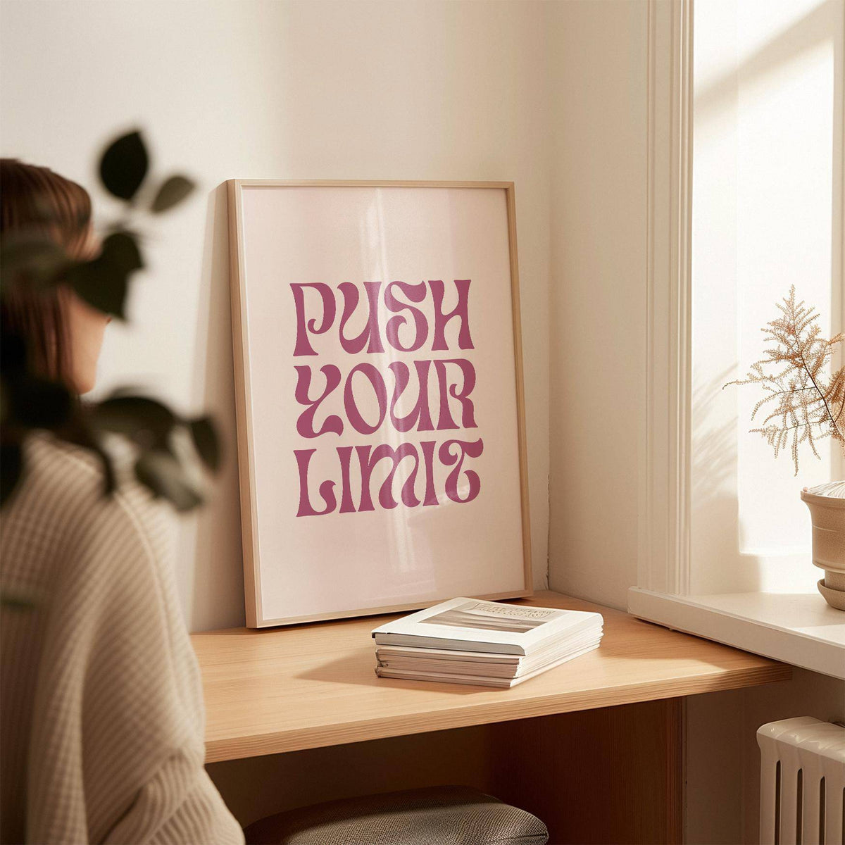 Quote motivational posters leaning on a wooden desk with books and a plant nearby in natural light