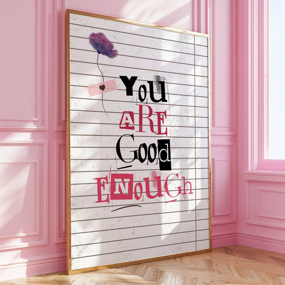 Framed print leaning on floor with motivational quote in pink black and white against pink walls