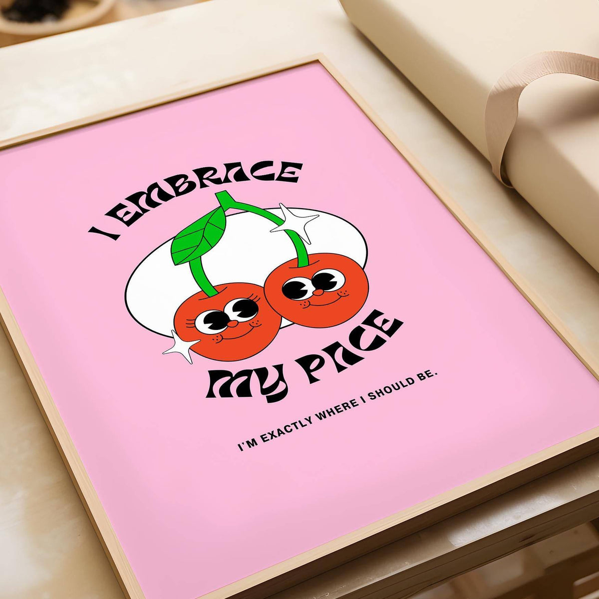 Framed print of pair of cherries with text I embrace my pace on pink background near gift box