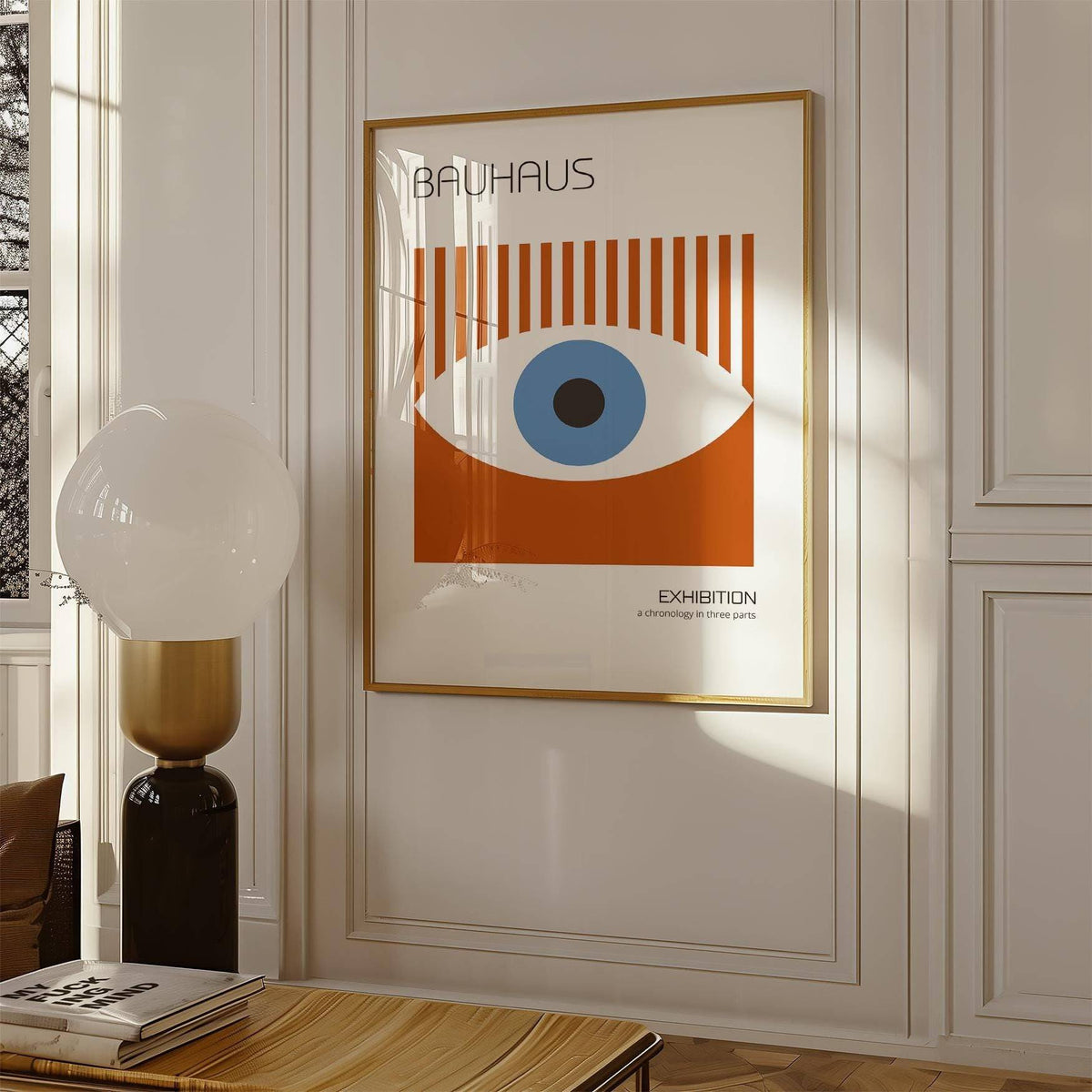 Print on a wall in a room showing a stylized eye graphic in blue and rust with vertical stripes and a lamp nearby