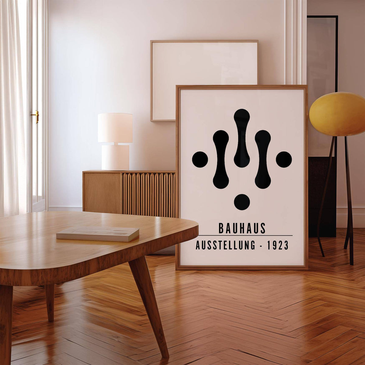 Print leaning on a floor featuring Bauhaus Art Black and White abstract shapes with a wooden sideboard and lamp