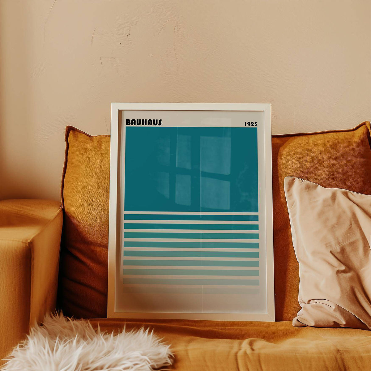 Framed Teal Blue Gradient Wall Art leaning on a mustard sofa with cushions and a white furry throw