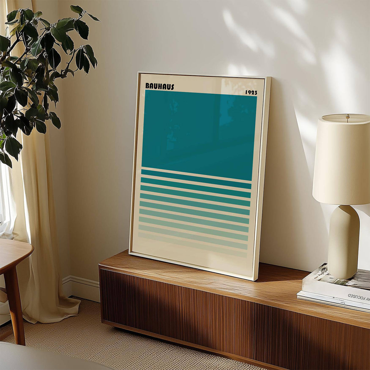 Print leaning on a cabinet teal blue gradient minimalist wall art with lamp and plant nearby