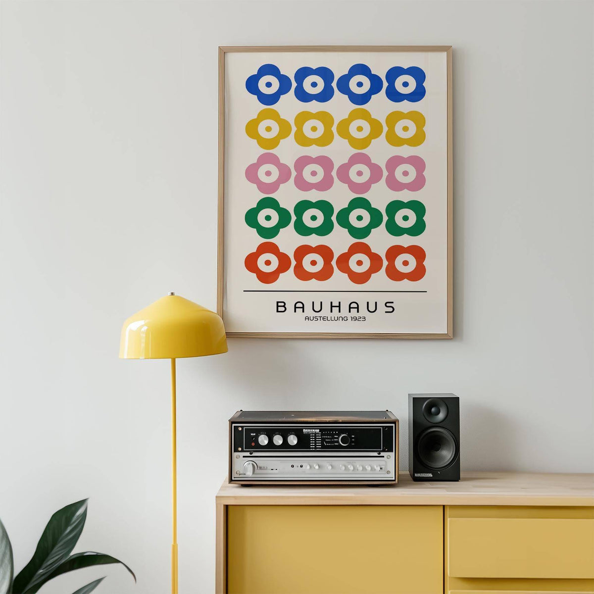 Bauhaus print design hung above a yellow sideboard with a retro speaker and yellow lamp