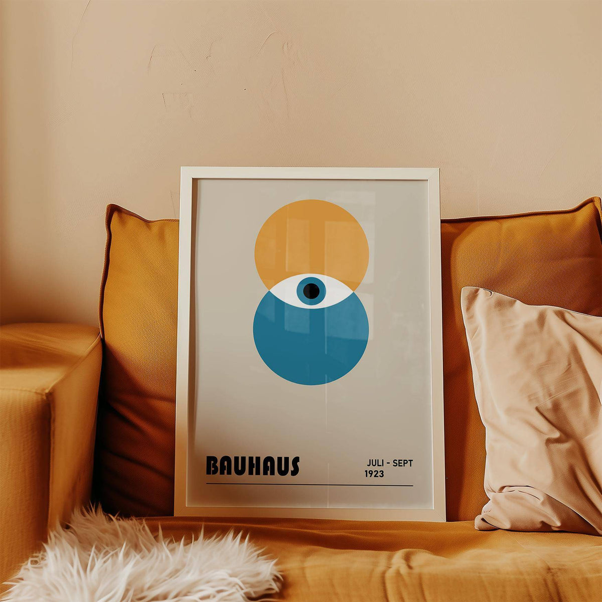 Framed Bauhaus painting of an abstract eye with blue and ochre circles leaning on a mustard sofa