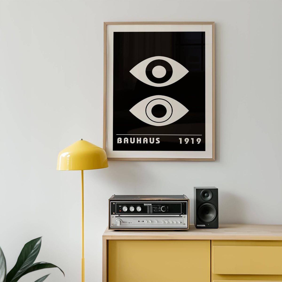 Eye Art wall print of two abstract eyes in black and white above a yellow cabinet with a speaker and stereo