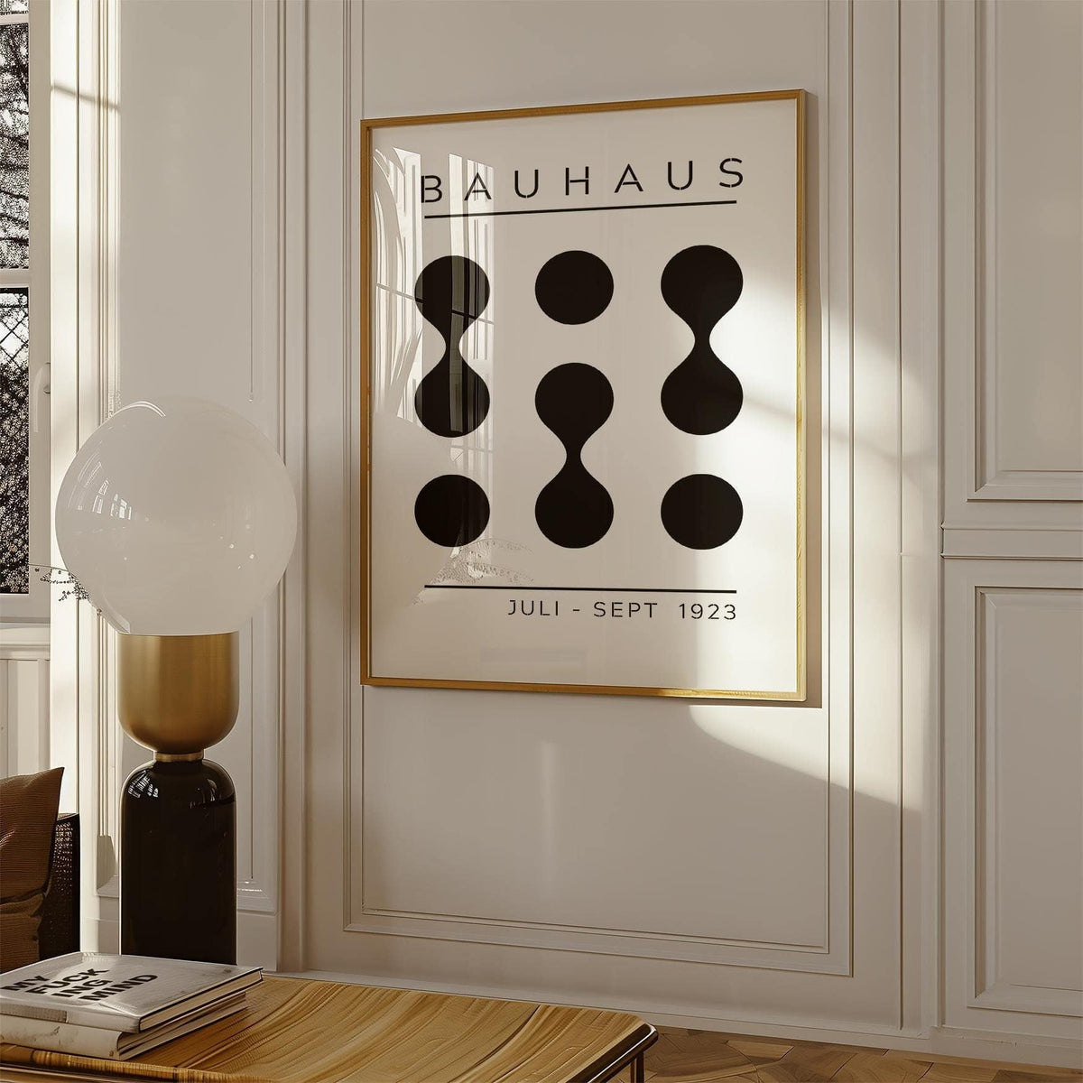 Black White Geometric Art framed print with abstract black shapes above a table with books in a beige room