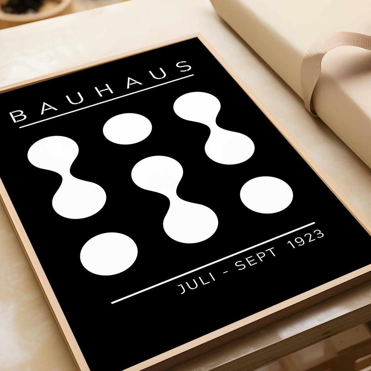 Framed Black and White Geometric Art with bauhaus shapes near a box with a cream ribbon