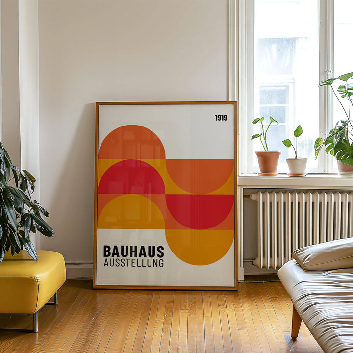 Print leaning on floor of colourful Bauhaus style geometric shapes by a plant and window in living room