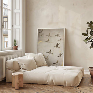 Print leaning on floor showing flying geese in grey and brown tones beside green plants