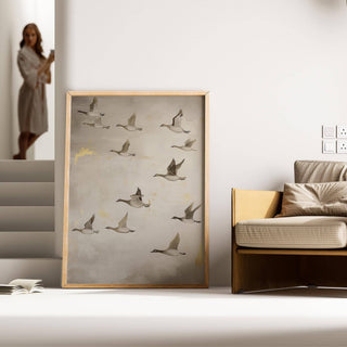 Oriental artwork print of flying geese with grey and brown tones next to a sofa