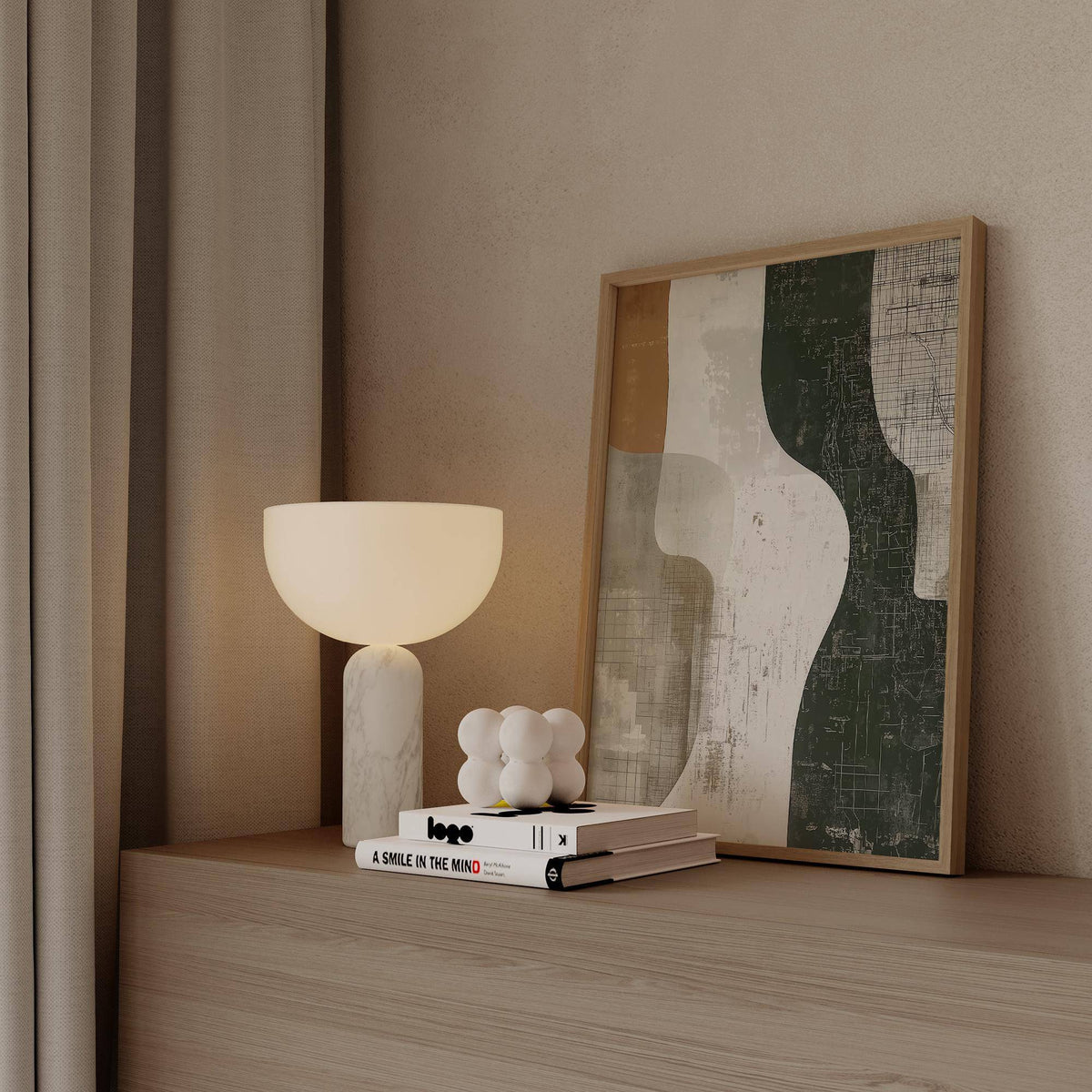 Framed Wabi Sabi Print with abstract earth tone shapes leaning on a wooden surface beside a curved lamp