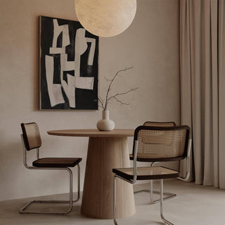 Wabi Sabi wall art with white abstract shapes on black above a round wooden dining table