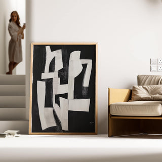 Wabi Sabi wall art with white abstract shapes on black leaning on the floor next to a sofa