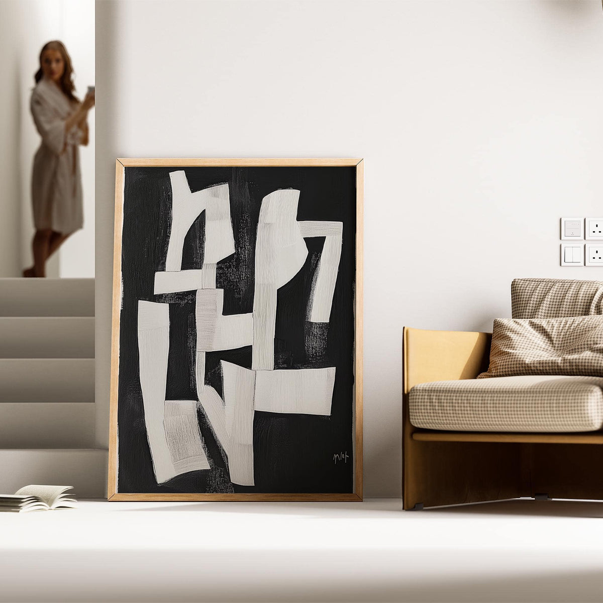 Wabi Sabi wall art with white abstract shapes on black leaning on the floor next to a sofa