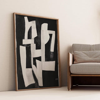 Print leaning on floor with abstract white shapes on black near a houndstooth cushion sofa