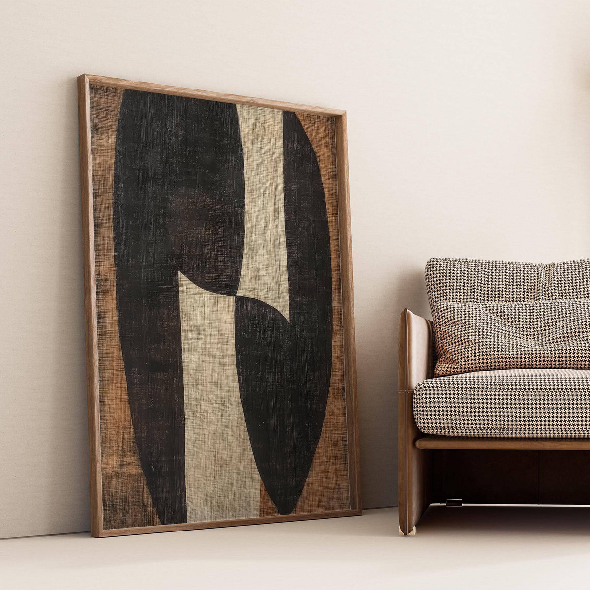 Zen wall art of abstract organic shapes in black and beige leaning on the floor next to checkered cushion sofa