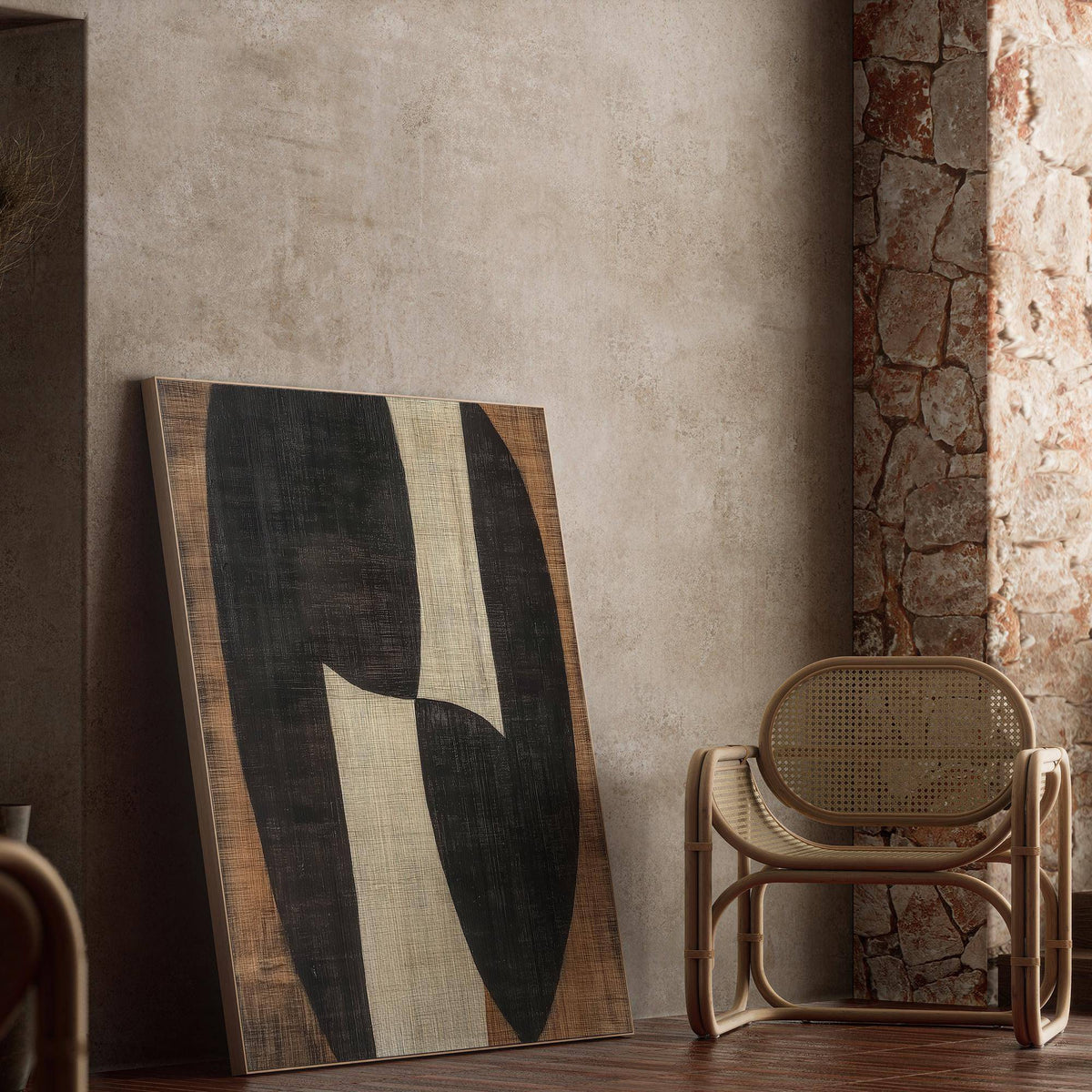 Print leaning on a wall showing abstract organic shapes in black, cream, and brown near a rattan chair