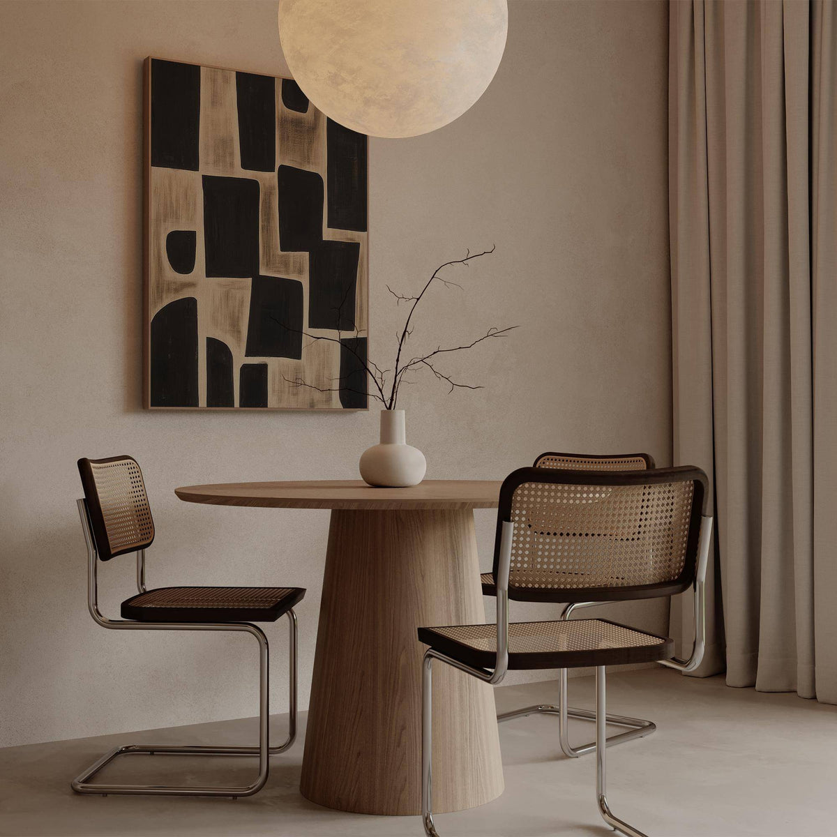 Wabi Sabi Artwork in black and beige abstract shapes on a wall in a dining area with a round wooden table and two chairs