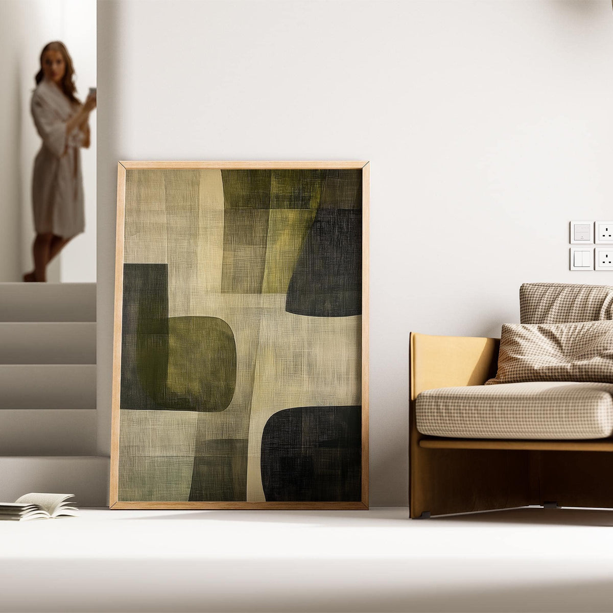 Abstract art print with green and black shapes leaning on the floor by a beige chair