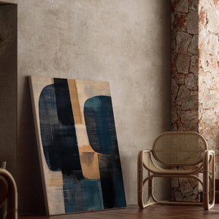 Print leaning on the floor of abstract shapes in navy and beige next to a rattan chair