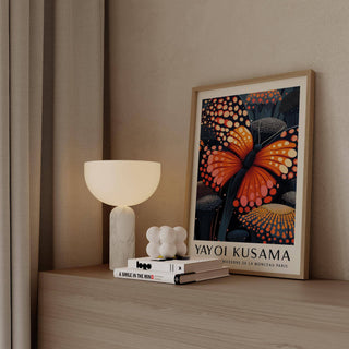 Poster Butterfly print with orange butterfly with dark blue spots leaning on a wooden shelf next to a white lamp