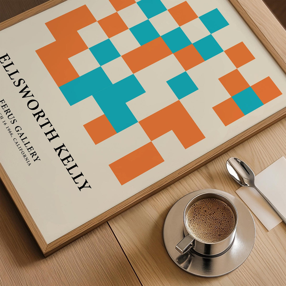Framed close-up of large geometric wall art with orange and blue squares on a wood table with a coffee
