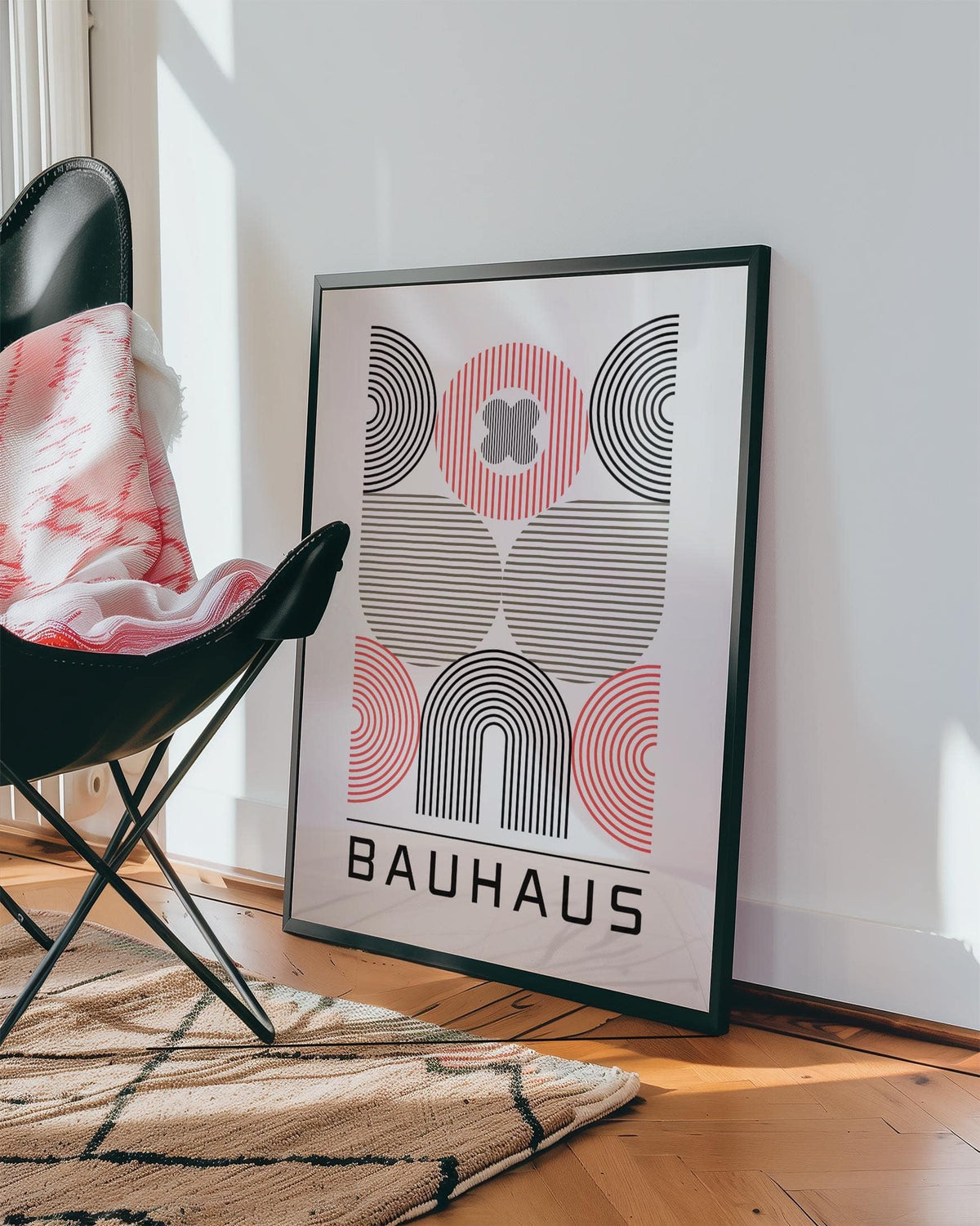 Wall Art for Home Office leaning framed print of abstract geometric shapes in black and red beside a black chair with a patterned throw