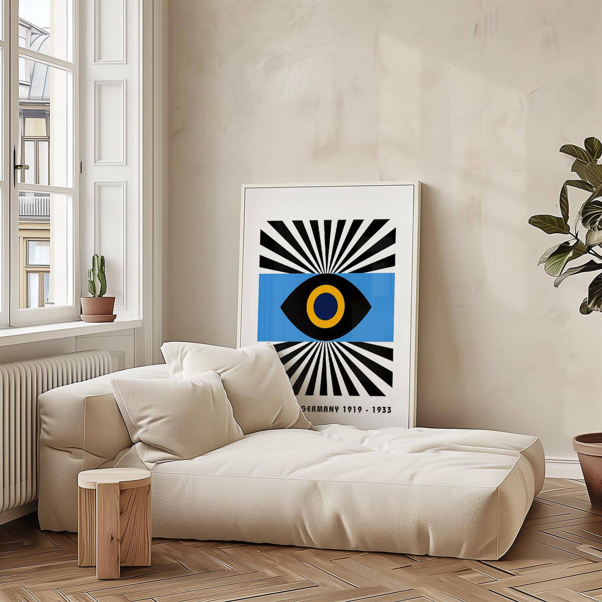 Print leaning on the floor of abstract eye graphic with black, blue and yellow in a living area with a plant