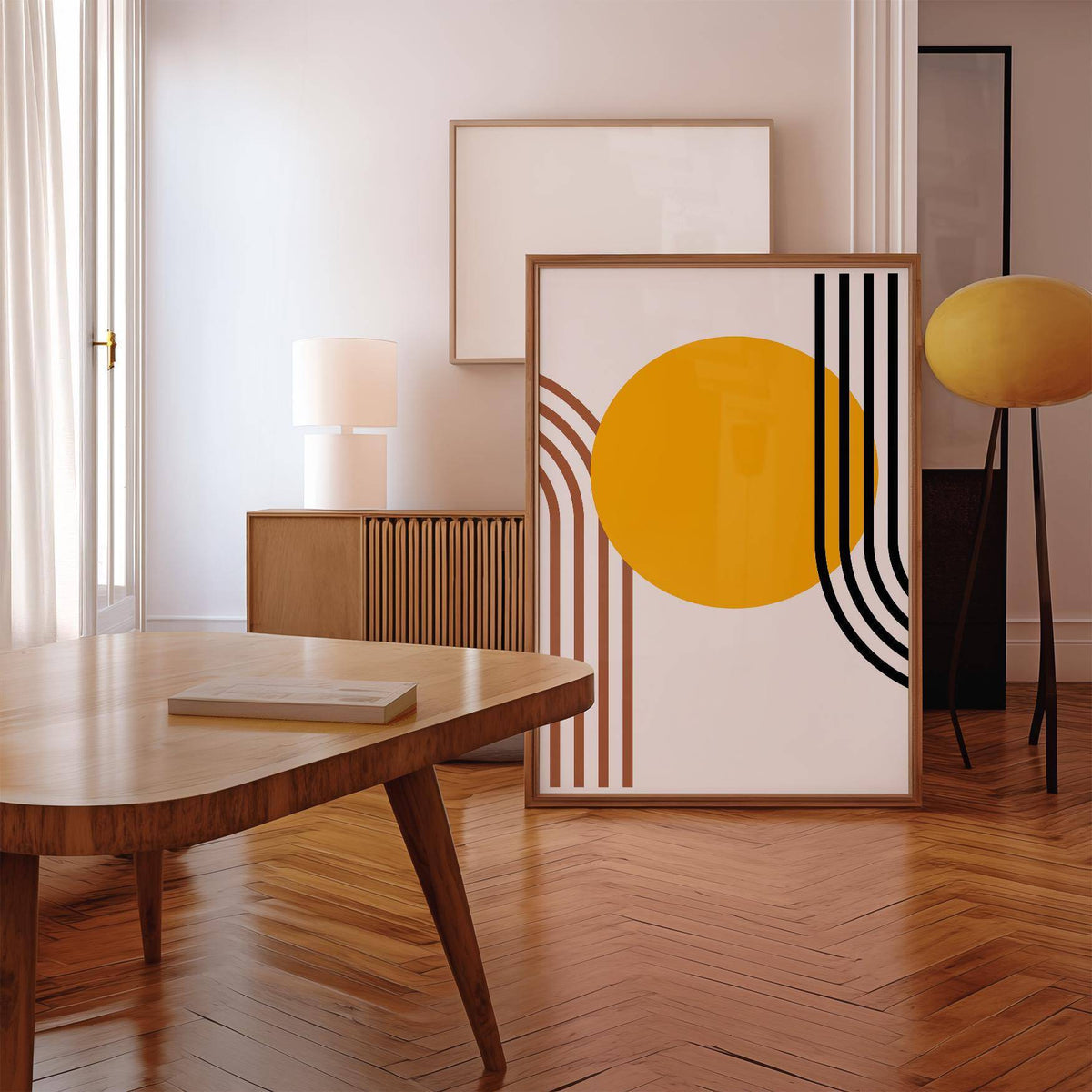 Print leaning on a wooden floor showing Bauhaus Sun Print with orange circle and black and brown lines beside a yellow lamp